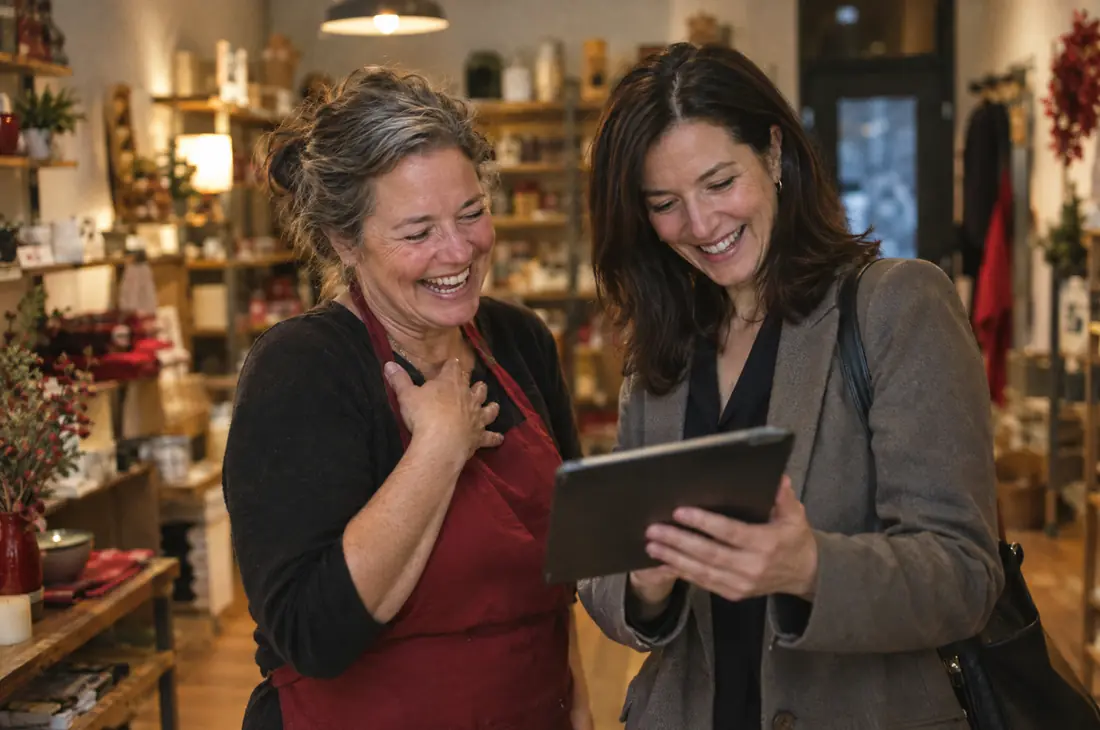 Business owner and consultant smiling at results on a tablet